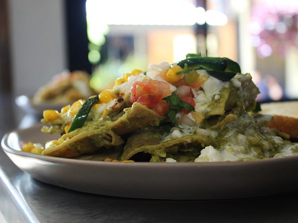 Chilaquiles verdes con rajas de poblano, elote, crema, queso fresco y pico de gallo.