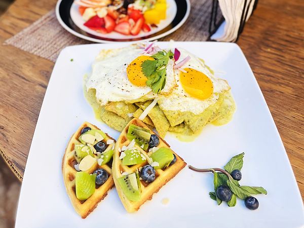 Chilaquiles verdes con dos huevos estrellados y waffles con kiwi, blueberries y almendra.